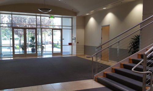 Empty lobby with glass doors and carpeted flooring.