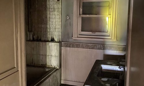 Dimly lit, old bathroom with a bathtub, sink, and window.